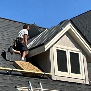 A residential roofing contractor on top of a black roof that had a roof replacement in Michigan