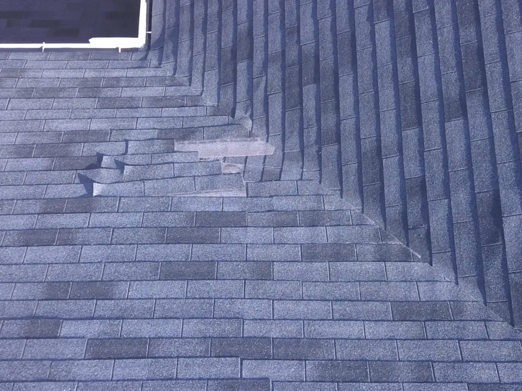 Detailed view of visibly damaged and displaced asphalt roof shingles by Performance Roofing and Siding in Royal Oak, MI