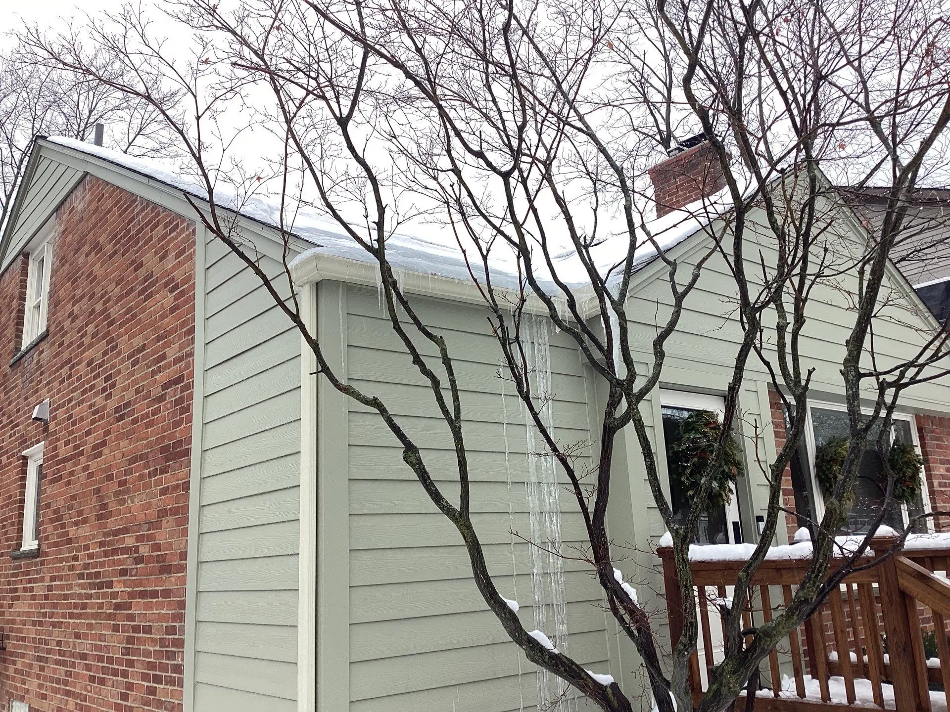 Close-up of gutter and siding with icicles and ice dam inspected by Performance Roofing and Siding in Birmingham, MI
