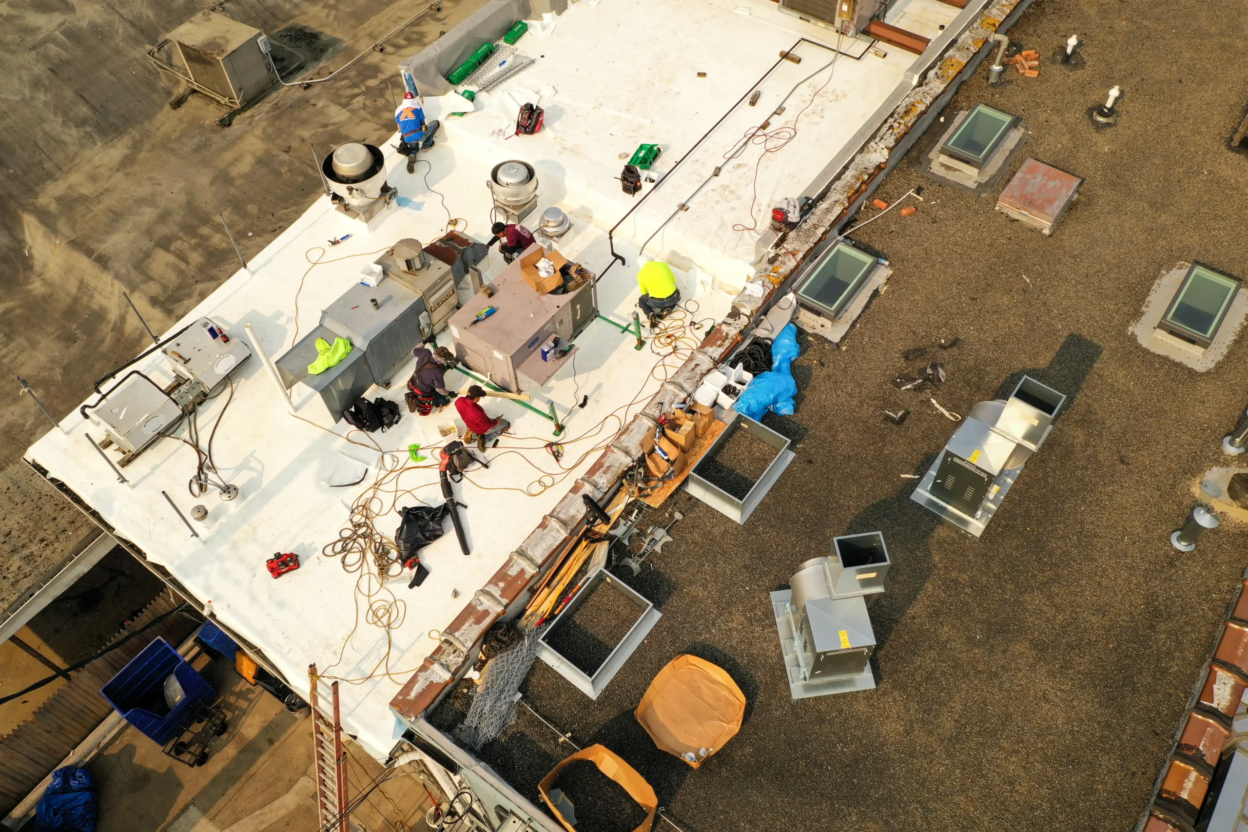 Performance Roofing & Siding crew installing and maintaining roofing systems on a commercial flat roof, with multiple tools, materials, and HVAC units visible, showcasing professional service for commercial clients.