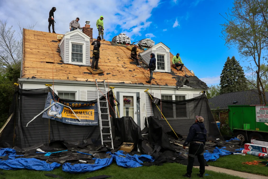 The large Performance Roofing and Siding crew at work on a full residential roof replacement, with extensive property protection in place.