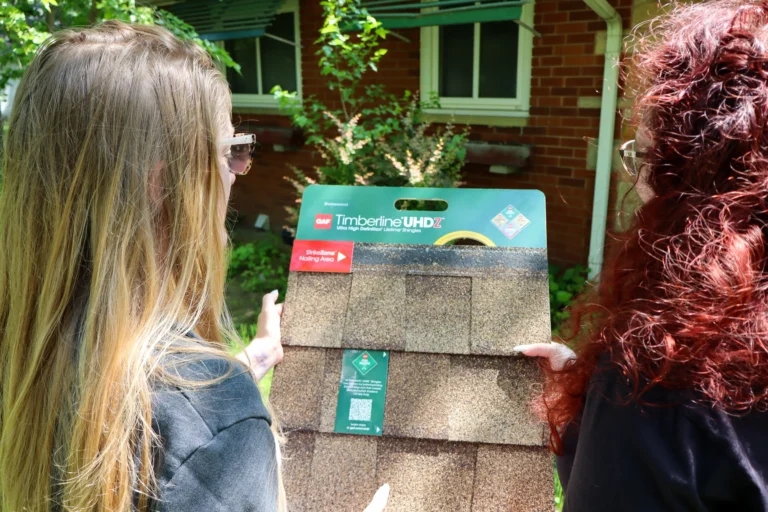 Performance Roofing & Siding specialist discussing shingle options with a homeowner during a personalized roof inspection walkthrough in front of a brick house in Pontiac, MI.