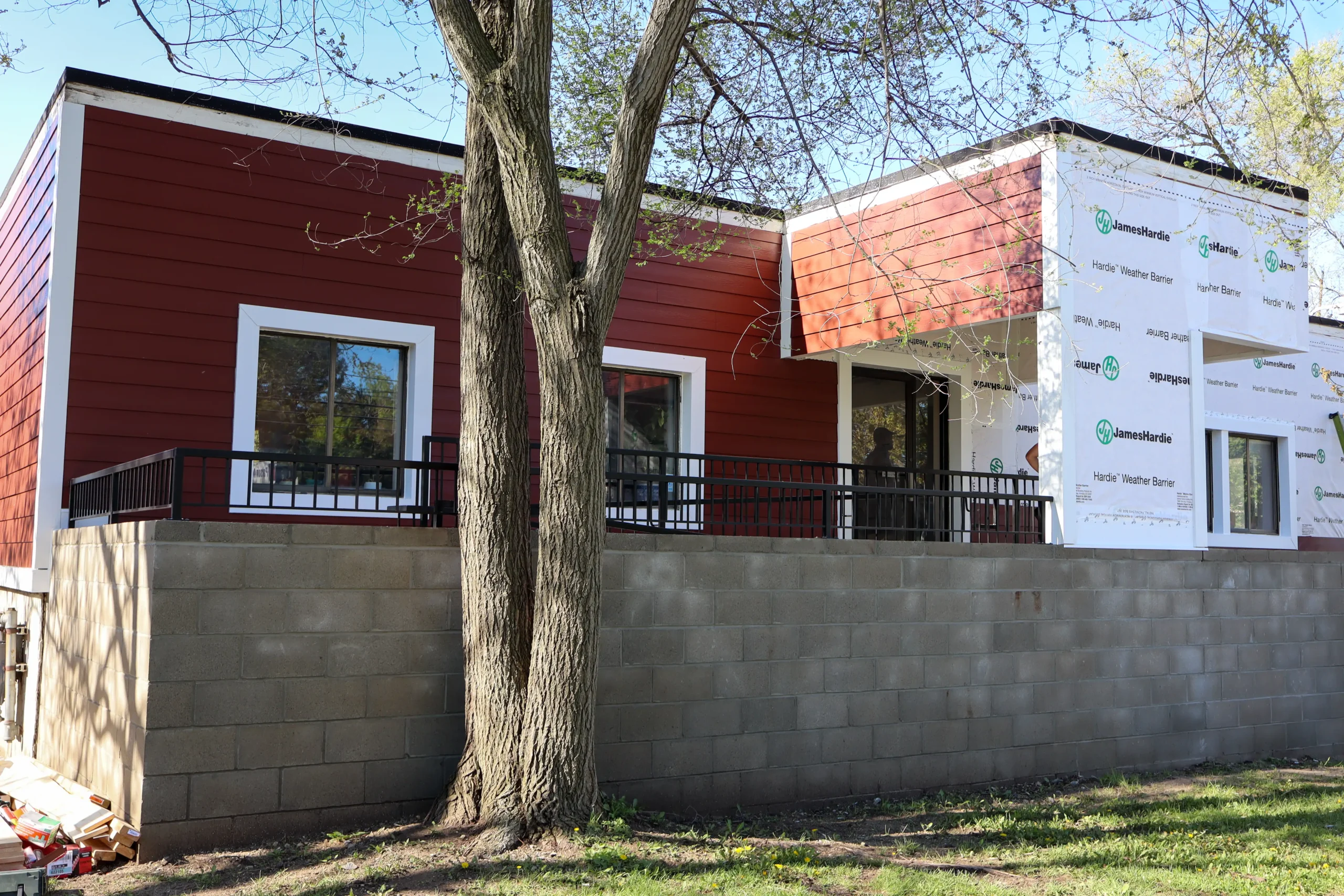 Modern home in the process of receiving new red siding, with insulated panels partially installed, showcasing exterior renovation services by Performance Roofing & Siding.